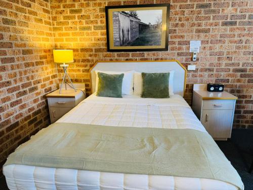 a bedroom with a large bed in a brick wall at Town and Country Motor Inn in Tamworth