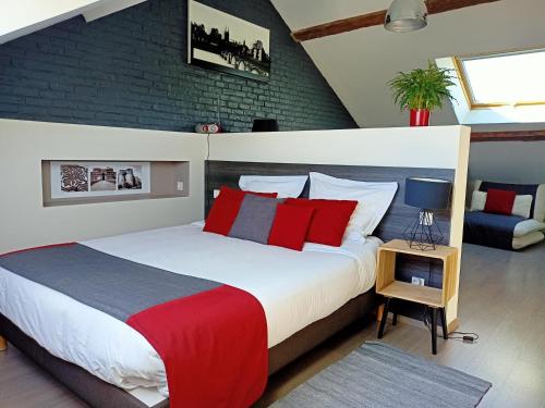Les Suites Angevines في أنجيه: غرفة نوم بسرير كبير ومخدات حمراء وزرقاء