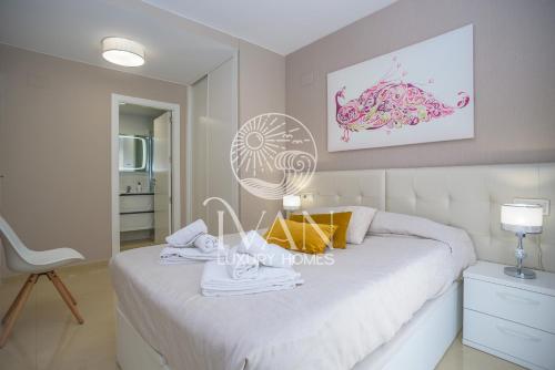 ein Schlafzimmer mit einem weißen Bett und einem weißen Stuhl in der Unterkunft Casa Andrea Ivan Luxury Homes 4ªPlta Sur 1ªLínea in Oropesa del Mar