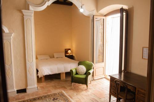 a bedroom with a bed and a green chair at Can Traver de Besalú in Maia de Montcal