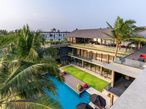 an aerial view of a building with a pool and palm trees at DORMERO Hotel Sri Lanka Hikkaduwa Beach in Hikkaduwa