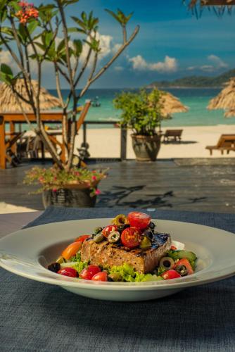 a plate of food with meat and vegetables on a table at BuBu Villa in Perhentian Island