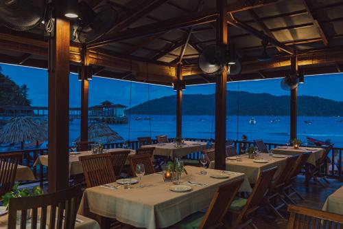 a restaurant with tables and chairs with a view of the ocean at BuBu Villa in Perhentian Island