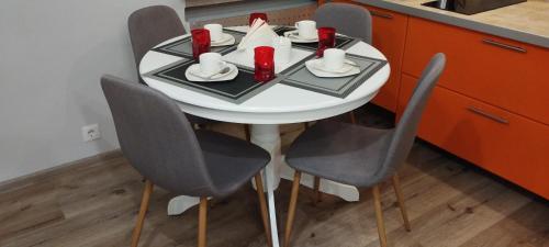 - une table blanche avec quatre chaises dans la cuisine dans l'établissement AveSol Apartment, à Riga