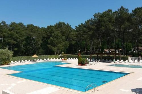 a large swimming pool with white chairs and a blue at Chalet confortable avec piscine in Gujan-Mestras