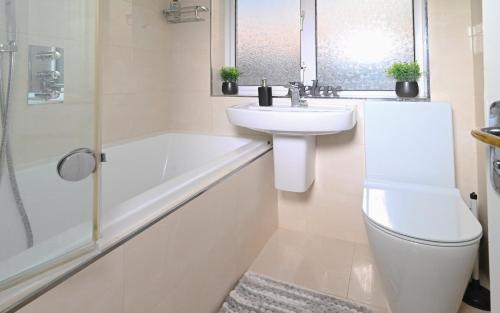 een badkamer met een wastafel, een toilet en een bad bij Urban Bliss 2BR Enfield Hideaway - Cosy Spot - Free Parking & Wi-Fi in Enfield