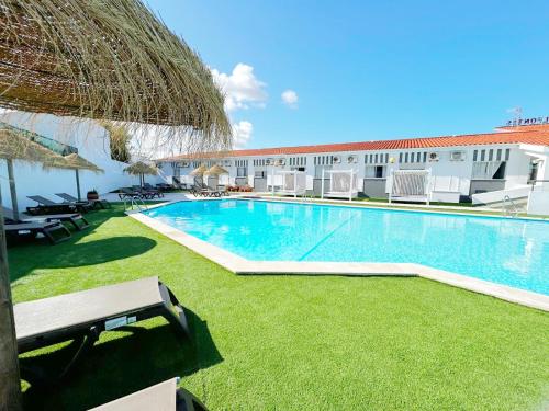 uma piscina com cadeiras e um edifício em Hotel HS Milfontes Beach - Duna Parque Group em Vila Nova de Milfontes