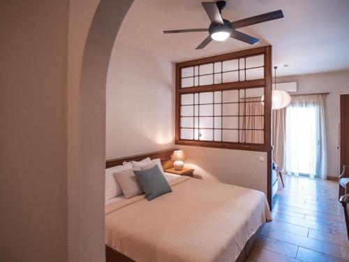 a bedroom with a bed with a ceiling fan at Dracos Hotel in Parga