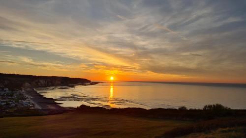 a sunset over a beach with the sun setting at LA TANIÈRE in Gueures