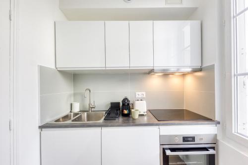 a kitchen with white cabinets and a sink at Le Nid Cozy - Face Gare De Corbeil in Corbeil-Essonnes