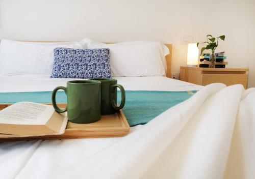 un letto con due tazze di caffè verde e un libro di Holihome_Chicky House FRN ad Alba Adriatica