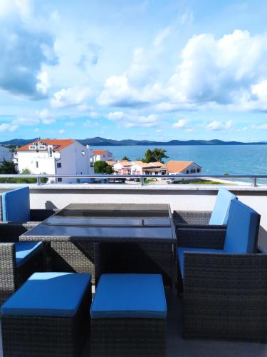 um pátio com mesas e cadeiras azuis e o oceano em Apartments Villa Lavanda em Zadar