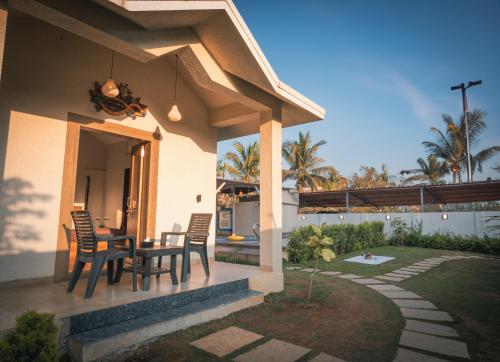 a patio with a table and chairs on a house at Iris Villa - Nagaon Beach in Nagaon