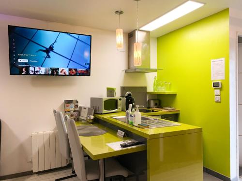 une cuisine avec un comptoir jaune et une télévision au mur dans l'établissement Domaine de la Besnerie Gites avec SPA Privatif à 10 min du Mont St Michel, à Tanis