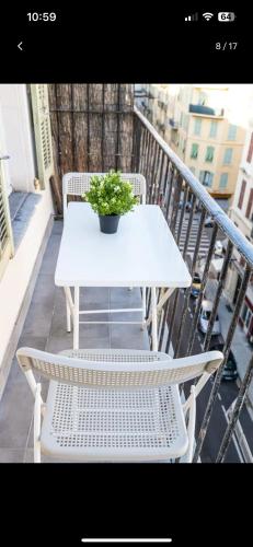une table et des chaises blanches sur un balcon avec une plante dans l'établissement Studio chaleureux, à Nice