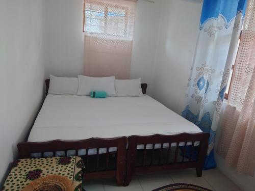 a small bedroom with a bed and a window at Flamingo Guest House ZNZ in Stone Town