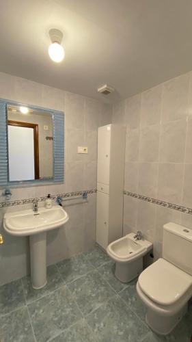a bathroom with a sink and a toilet and a mirror at Ático - Avenida Galicia 60 in Finisterre