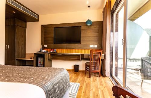 a bedroom with a bed and a desk with a television at The Belvedere Himalayan Retreat, Mcleodganj, Dharamshala - By Leisure Hotels in McLeod Ganj