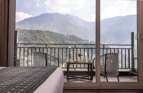 a bedroom with a balcony with a view of a mountain at The Belvedere Himalayan Retreat, Mcleodganj, Dharamshala - By Leisure Hotels in McLeod Ganj