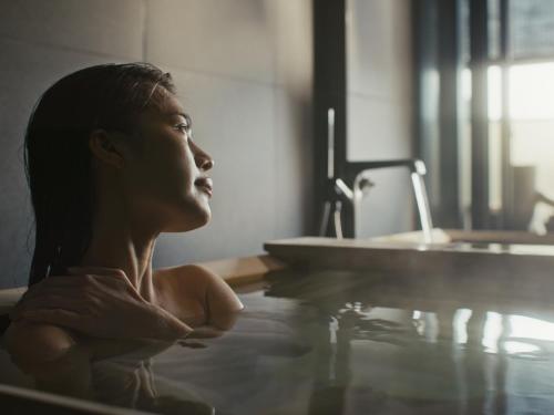a woman is sitting in a bath tub at SOKI ATAMI in Atami