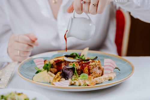 a person eating a plate of food with a fork at Hotel Kaštieľ Mojmírovce in Mojmírovce