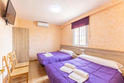 two beds in a room with purple sheets at Los Naranjo in Villamanrique de Tajo