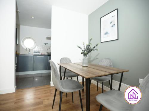 uma sala de jantar com uma mesa de madeira e cadeiras em Victoria Wharf, Stunning Cardiff Bay Apartment em Cardiff