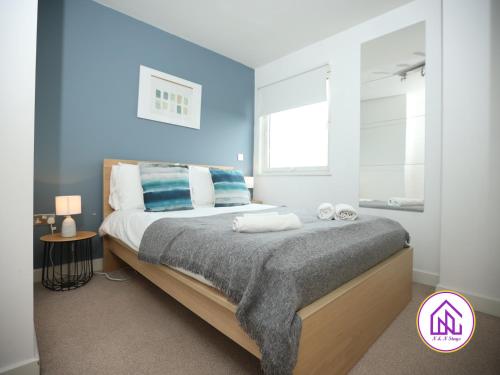 um quarto com uma cama grande e paredes azuis em Victoria Wharf, Stunning Cardiff Bay Apartment em Cardiff
