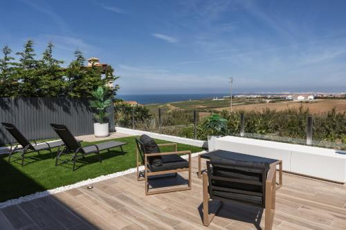 a patio with chairs and a table and the ocean at Serenidade do Mar in Atouguia da Baleia