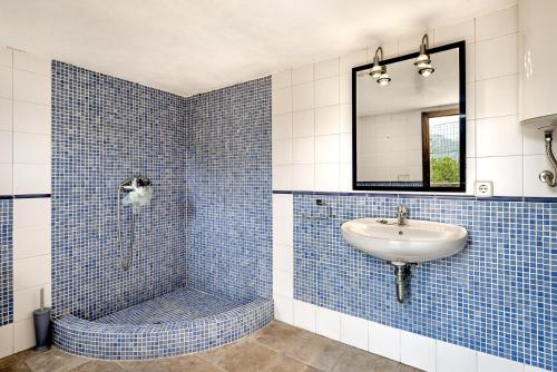 y baño de azulejos azules con lavabo y ducha. en Villa Sestadors en Selva