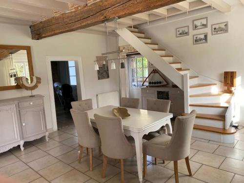 a dining room with a table and chairs and stairs at Grande maison familiale La Tuilerie in Bourriot-Bergonce