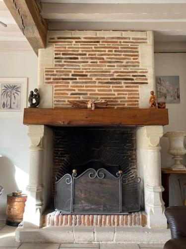 a stone fireplace with a brick wall in a living room at Grande maison familiale La Tuilerie in Bourriot-Bergonce