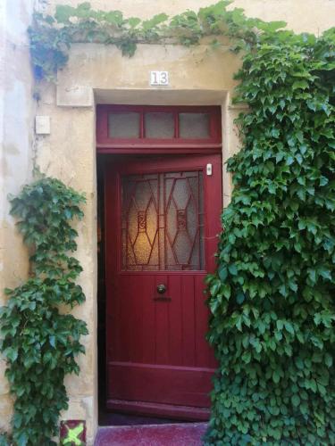une porte rouge sur un bâtiment avec lierre dans l'établissement CALM&ART INTRA-MUROS, à Avignon