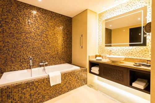 a bathroom with a tub and a sink and a mirror at Dream Inn Apartments - Luxury 2BR in Marjan Island Close to Beach in Ras al Khaimah