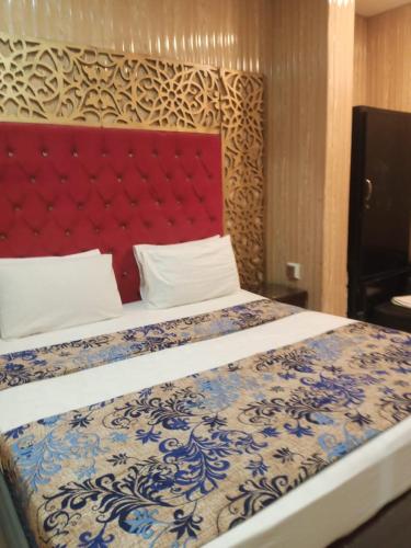 a bedroom with a large bed with a red headboard at Glorious Guest House & Hotel in Multan