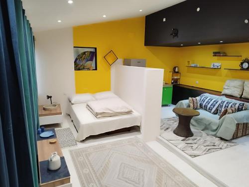 - un salon avec des murs jaunes et un canapé dans l'établissement Jardenia apartments, à Skopje