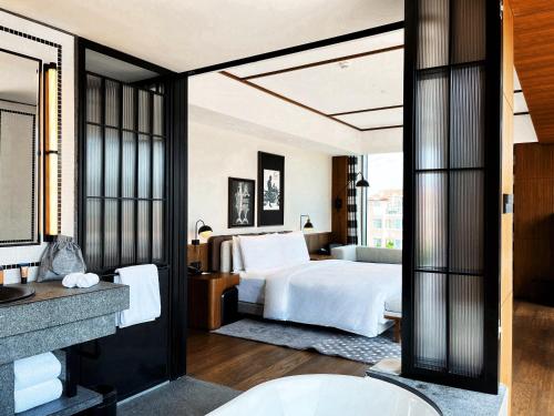 青島市にあるFlow and Co. Qingdao, Autograph Collectionのベッドとバスルーム付きのホテルルームです。
