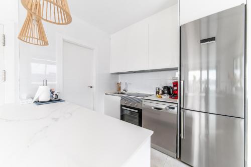 a white kitchen with a stainless steel refrigerator at Villa Armonia - Heated Pool - Countryside Charm - by OYOOSTAYS in Daya Nueva