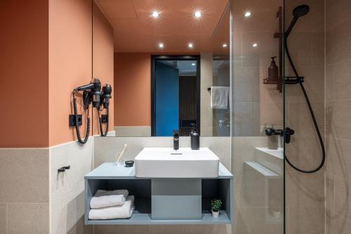 ein Bad mit einem Waschbecken und einer Dusche in der Unterkunft The Base Munich in München