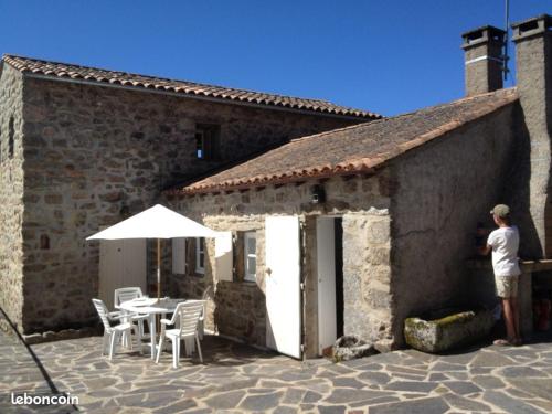 un homme debout à l'extérieur d'un bâtiment avec une table et un parasol dans l'établissement Domaine Sainte Germaine 4pers, à Luc