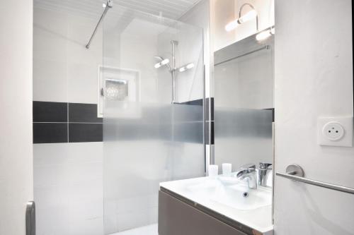 a white bathroom with a sink and a shower at The Lighthouse - Maison, 800m à pied du centre in Barneville-Carteret