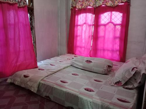 a bedroom with pink curtains and a large bed at Komodo homestay in Komodo