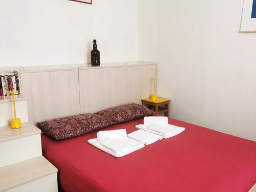 a red bed with three white towels on it at B&B Le Noci in Ascoli Piceno