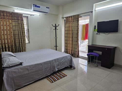1 dormitorio con 1 cama, TV y silla en Sweet Rest Dhaka, en Dhaka