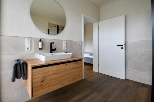 a bathroom with a white sink and a mirror at Ammerhuus Boardinghomes in Edewecht