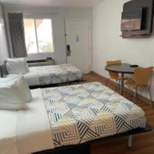 a hotel room with two beds and a table and a table at Motel 6-Van Horn, TX in Van Horn