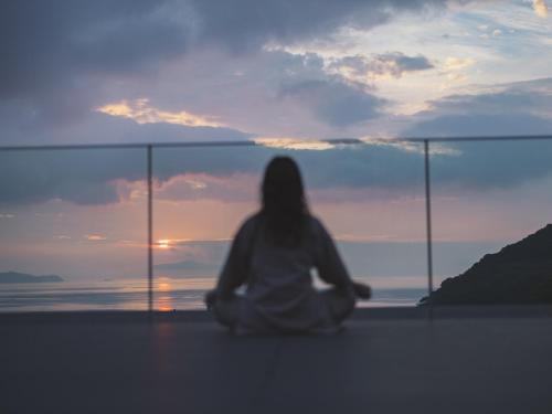 a woman sitting on the ground looking at the sunset at SOKI ATAMI in Atami
