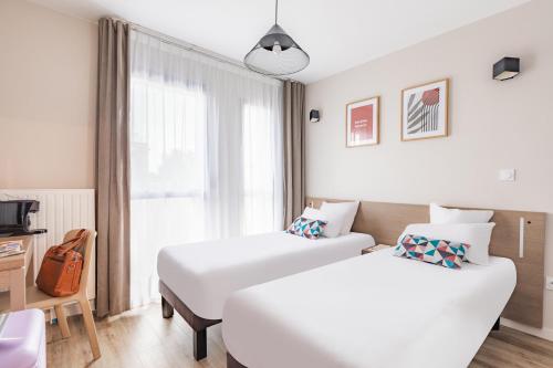 a hotel room with two beds and a window at Appart'City Confort Angers in Angers