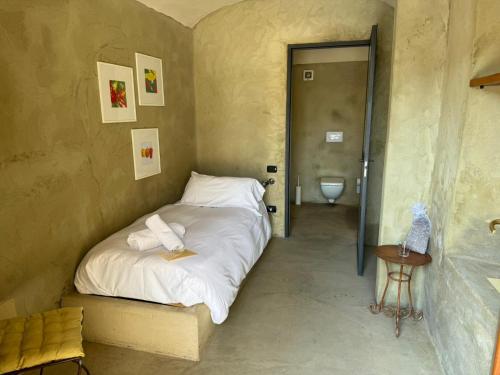 a bedroom with a bed with white sheets and a toilet at Ca' Villa Club Agriturismo in Gabiano
