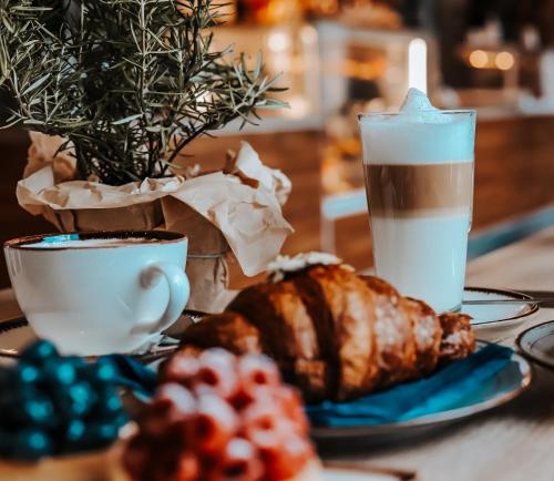 a table with a cup of coffee and a plate of food at Hotel Szydłowski in Gdańsk